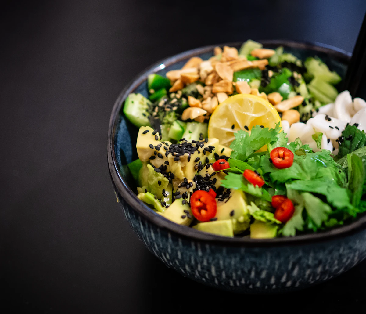 Ciotola di verdure, avocado e semi su fondo scuro